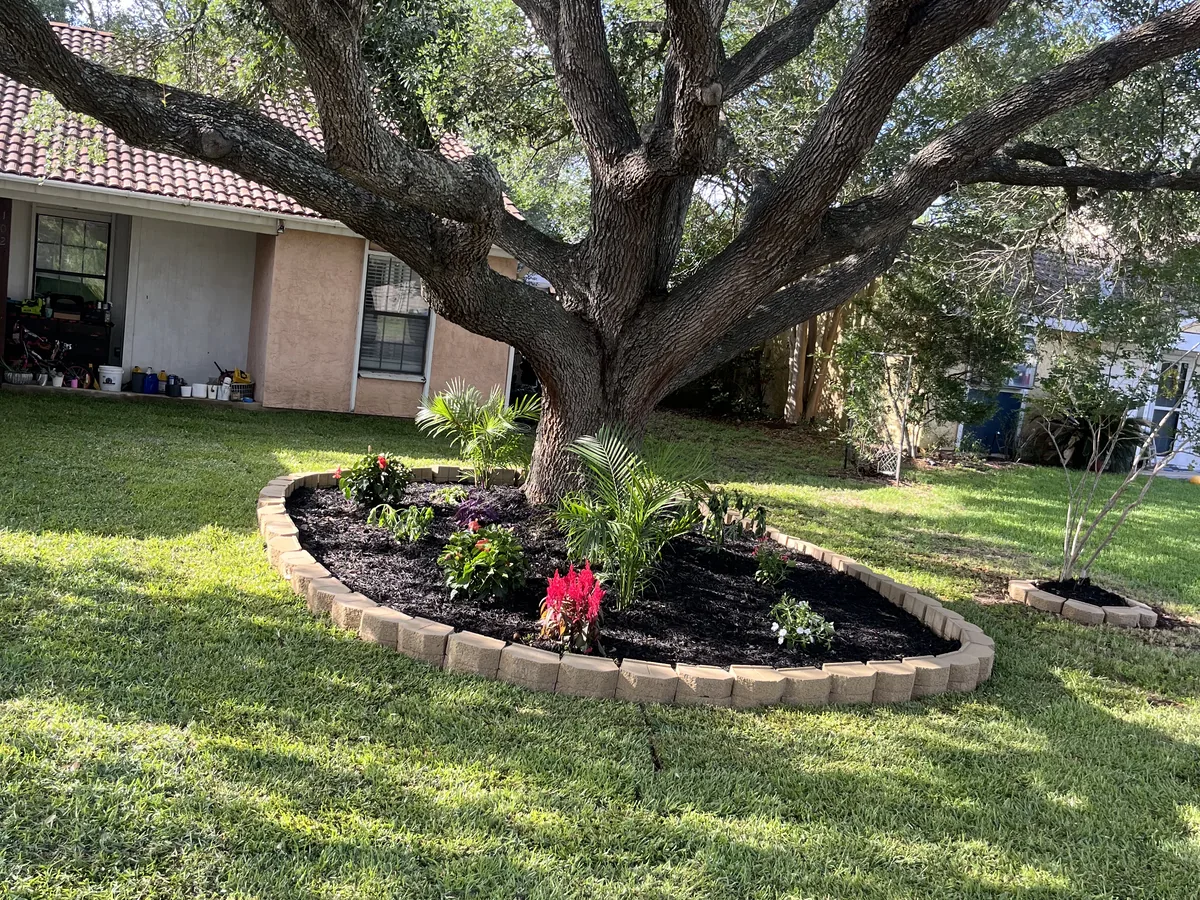Mulch tree ring with flowers and a stone block border